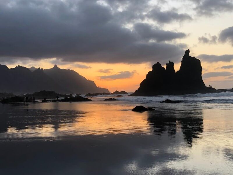 Sunset over Benijo Beach in northern Tenerife, with volcanic rock formations reflecting on the water.